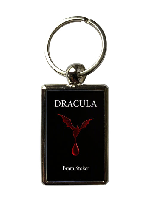 A rectangular keychain with a black face featuring the word 'DRACULA' in white at the top, a red bat-and-drop symbol in the center, and 'Bram Stoker' in white at the bottom. The keychain has a silver metal border and a silver split key ring, shown on a plain white background.