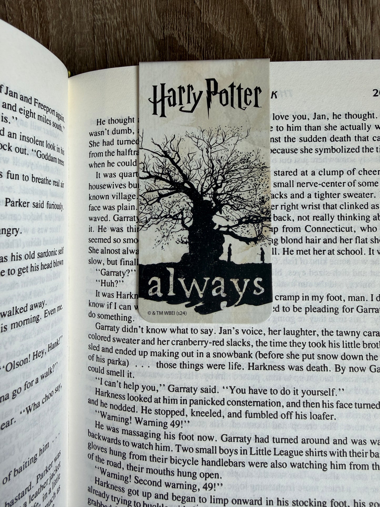 Book with a bookmark featuring 'Harry Potter' and the word 'always', on a wooden surface.