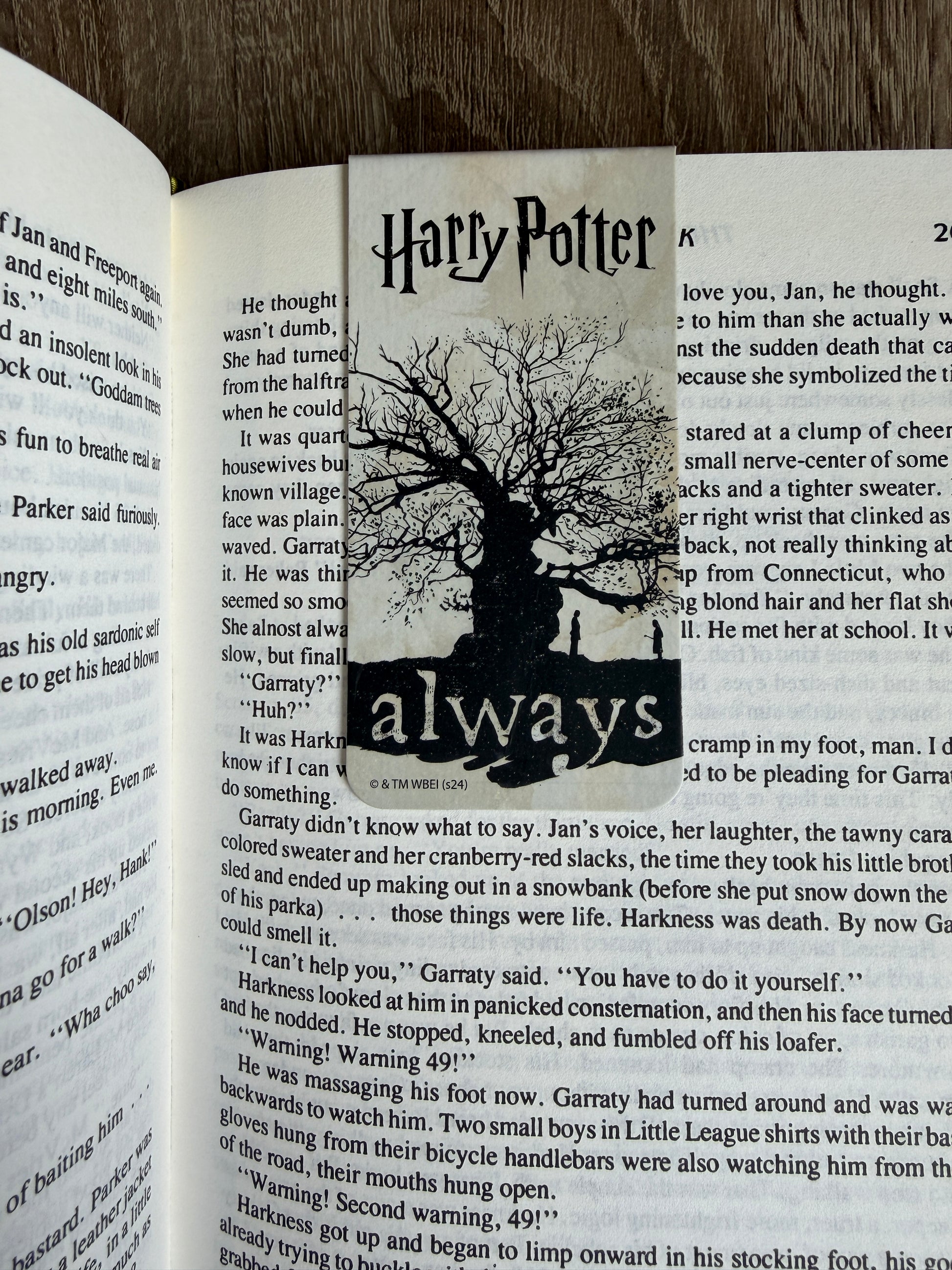 Book with a bookmark featuring 'Harry Potter' and the word 'always', on a wooden surface.