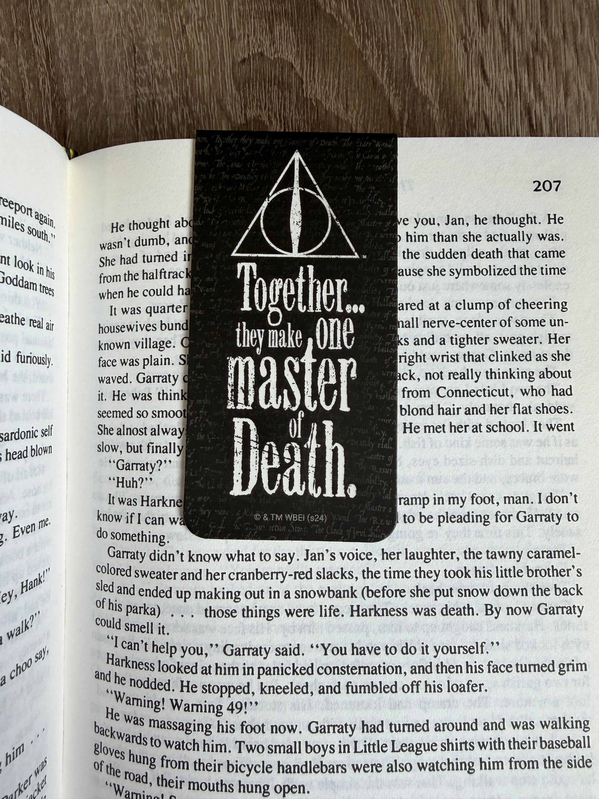 Book with a bookmark featuring a quote from 'Harry Potter' on a wooden surface