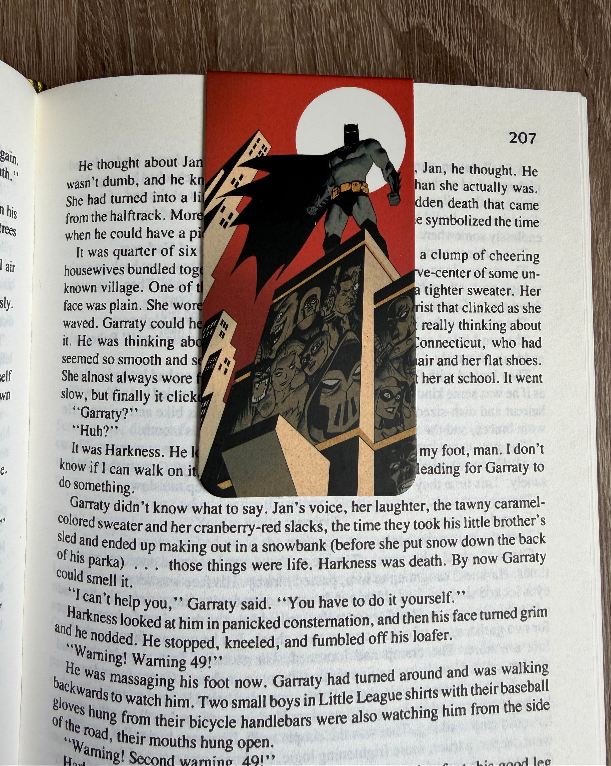 Decorative bookmark with a design of a character and cards on an open book.