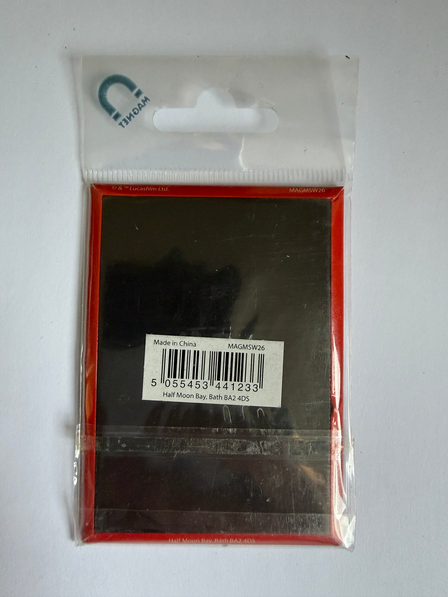 Small black rectangular object in clear packaging with a visible barcode on a white background
