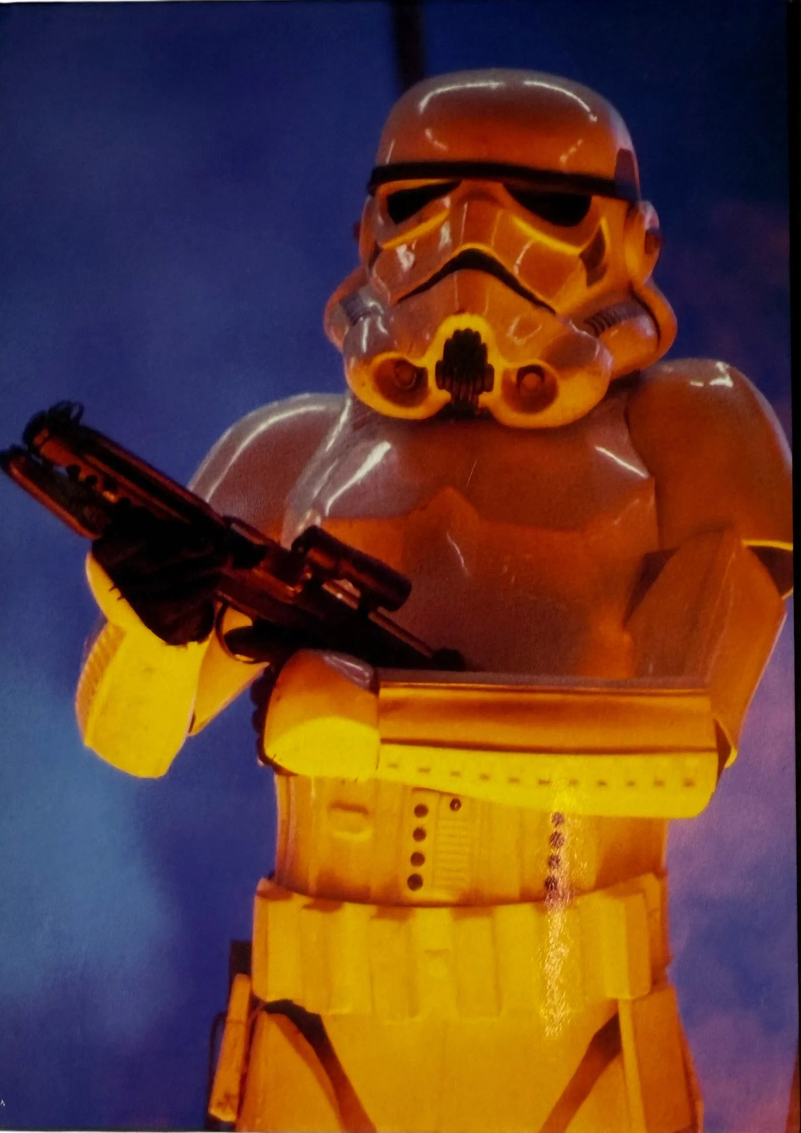 Yellow stormtrooper figure from Star Wars holding a weapon against a blue background