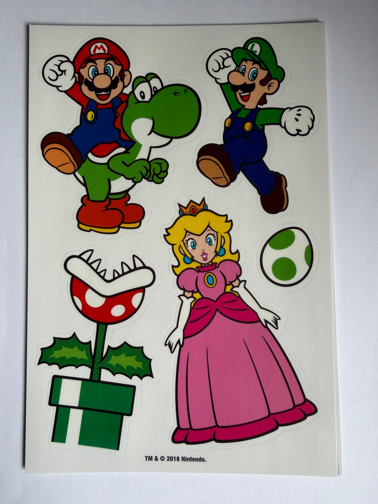 Cartoon characters including Mario, Luigi, Princess Peach, Yoshi, and a flower-like enemy on a white background.