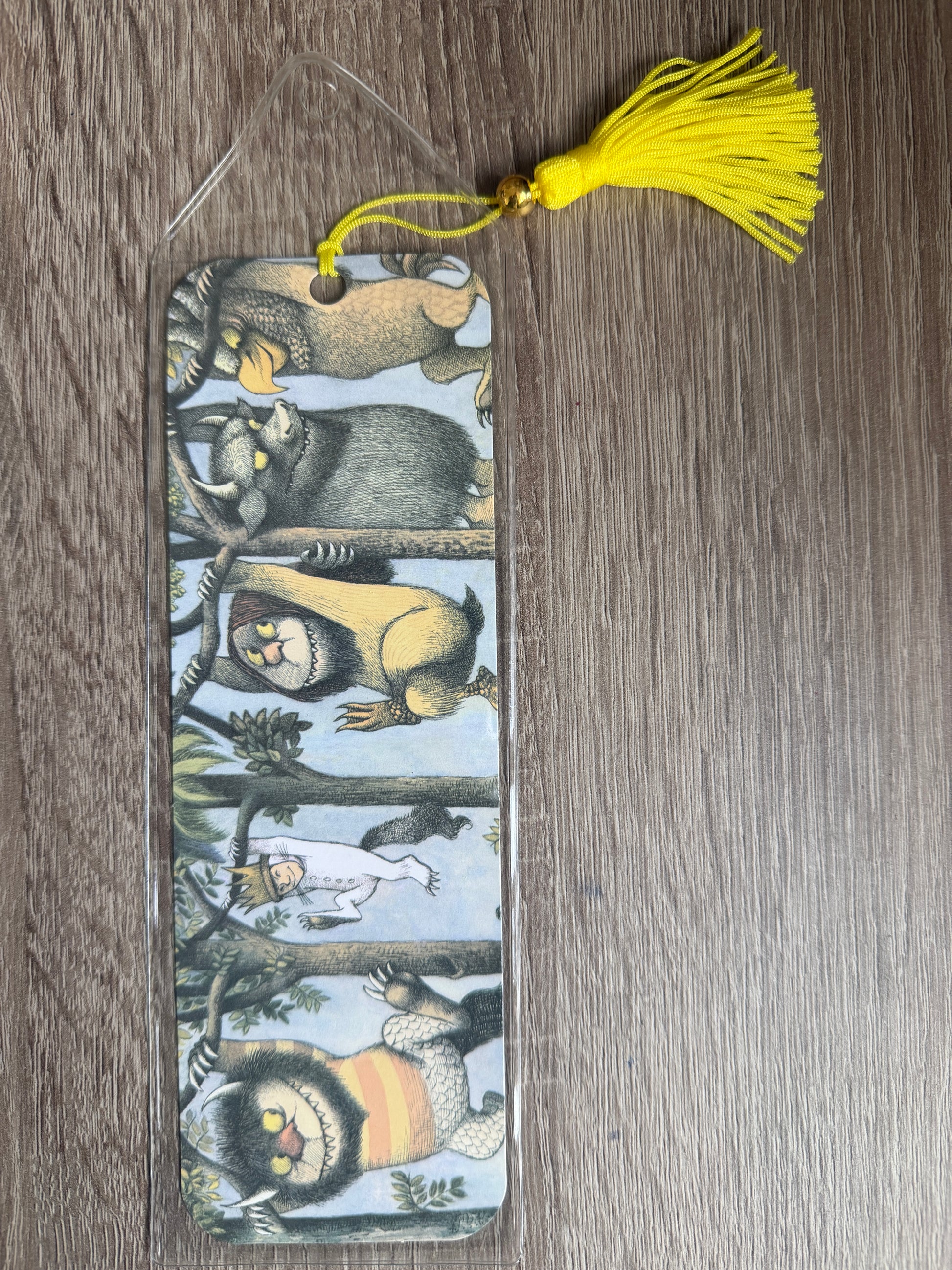 Bookmark with animal illustrations and a yellow tassel on a wooden surface