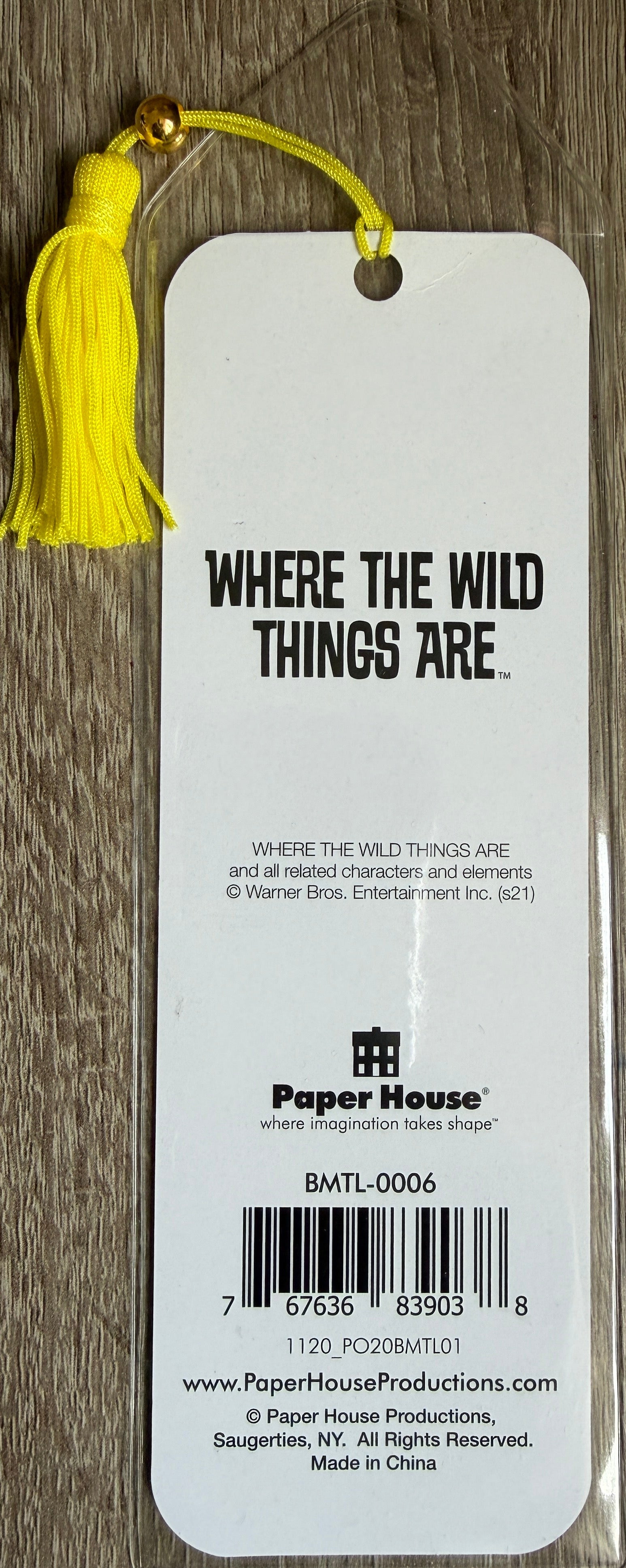 Bookmark with yellow tassel and 'Where the Wild Things Are' text on a wooden surface